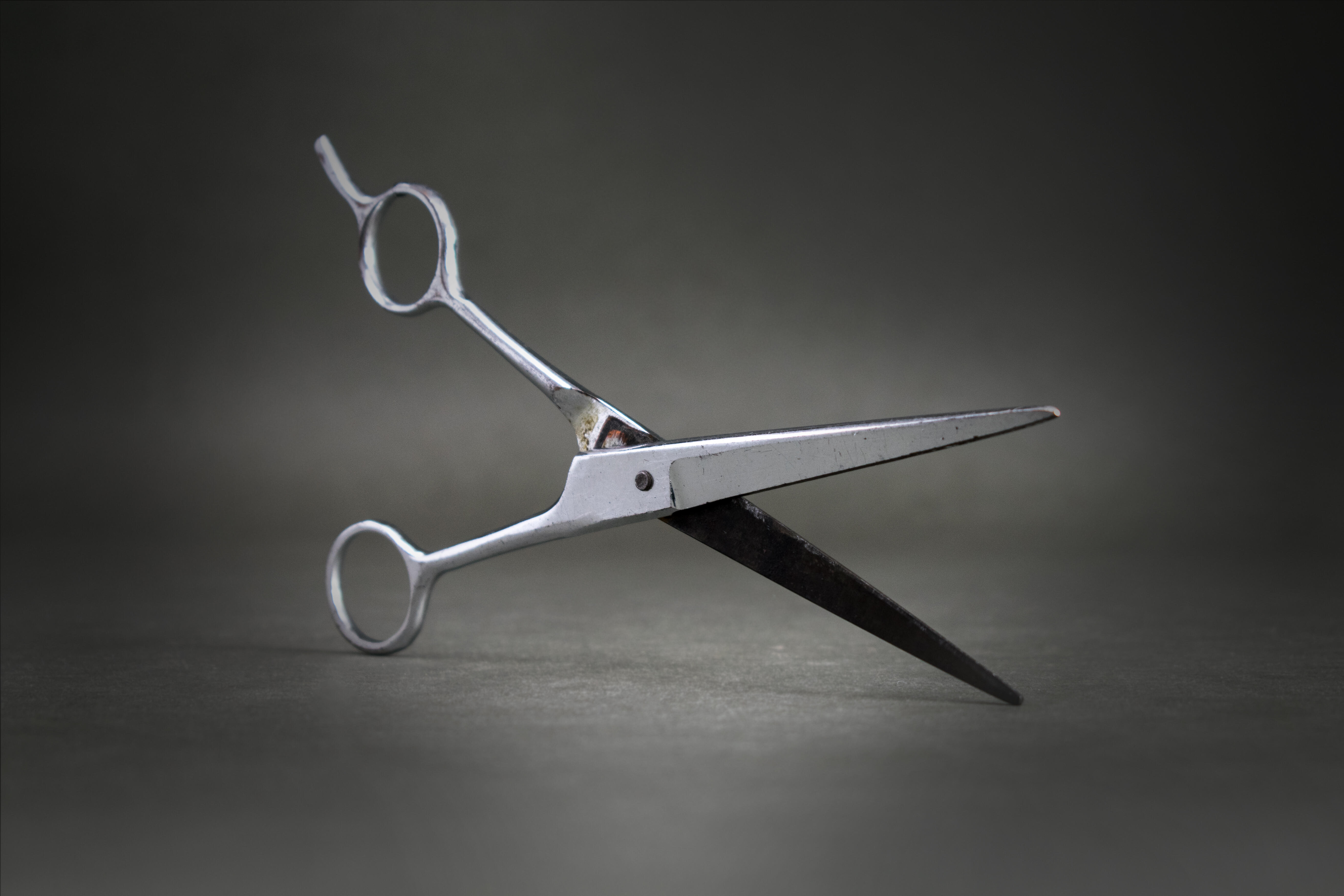 Das Bild zeigt eine Schere aus Metall mit einem festen Fingerhaken und Rost- und Gebrauchsspuren.