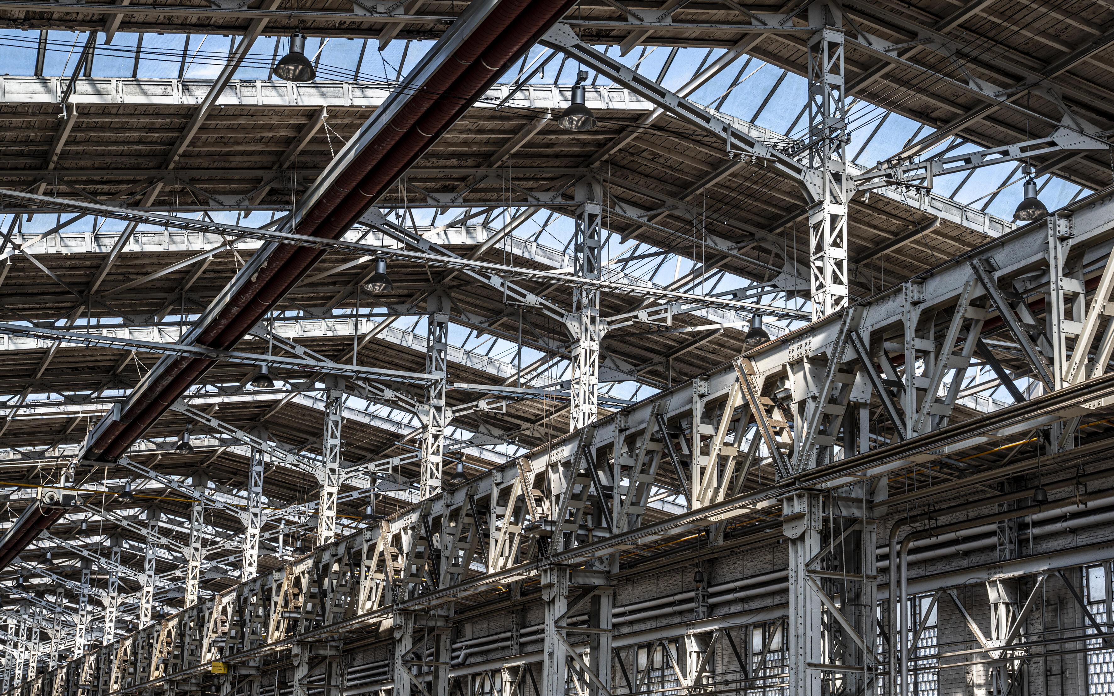 Auf dem Foto ist das Hallendach der alten Industriehalle zu sehen, in der das Museum Selma entsteht. Es sind vor allem Stahlträger und ein spitzes Glasdach zu sehen, durch das das viel Licht einfällt.