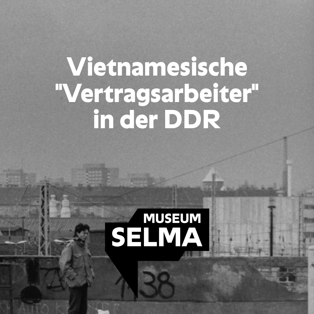 Auf einer schwarz-weiß Fotografie sieht man einen vietnamesisch stämmigen Mann mit zwei kleinen Taschen vor einer Mauer stehen, die mit Graffiti besprüht ist. Im Hintergrund stehen Industriebauten und Hochhäuser.