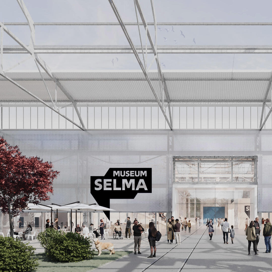 The green outdoor area of an industrial hall where people are chatting and the large logo of the Selma Museum can be seen.