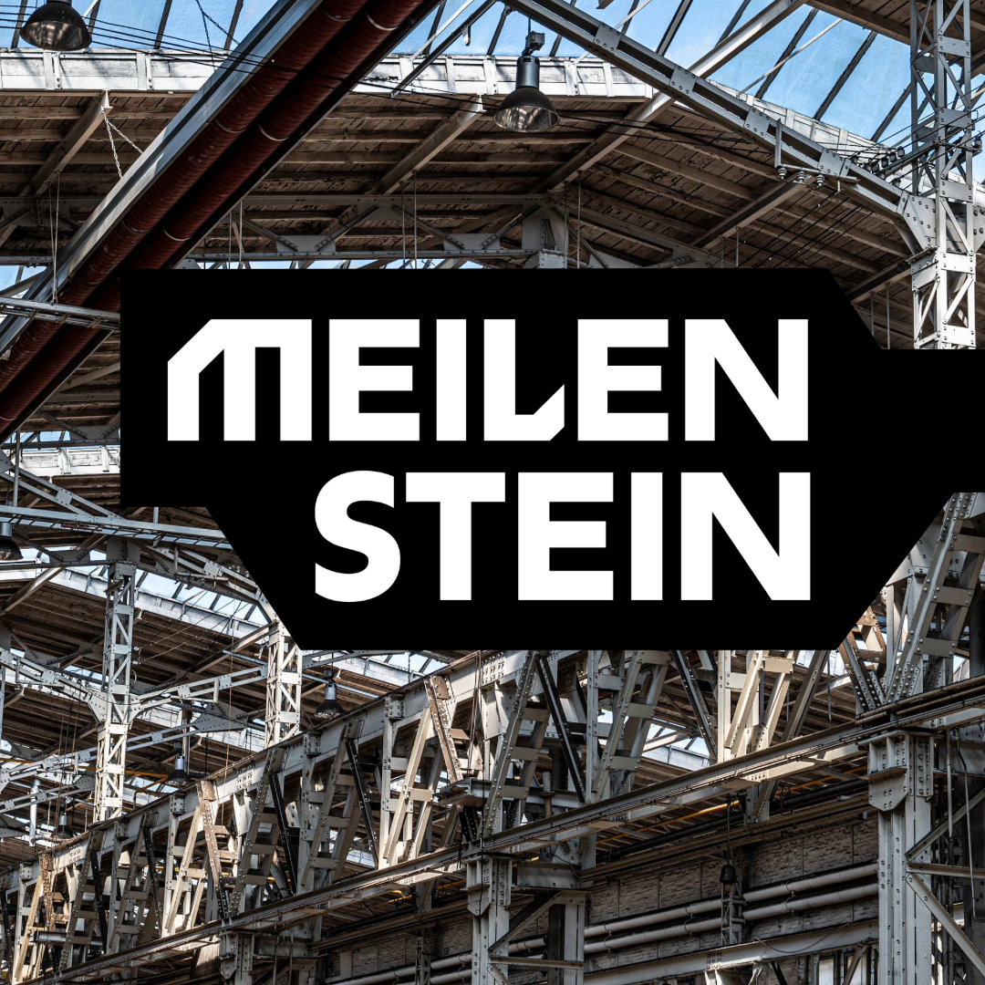 Der Schriftzug "Meilenstein" vor dem Hintergrund eines Blicks in die Halle 70 in Köln-Kalk, wo das Museum Selma entsteht.