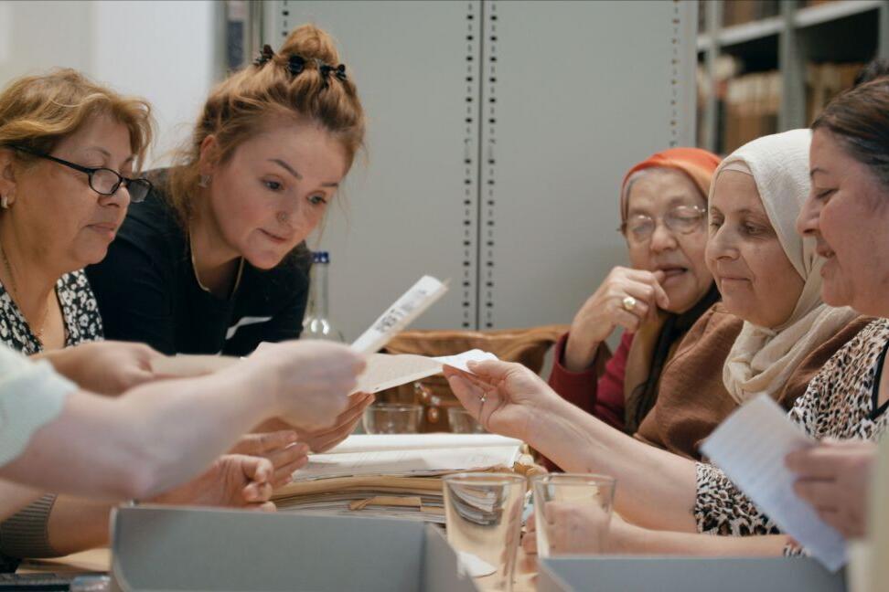 Six women sit opposite each other at a table and show copies of the ‘Möllner Briefe’ (Mölln Letters).