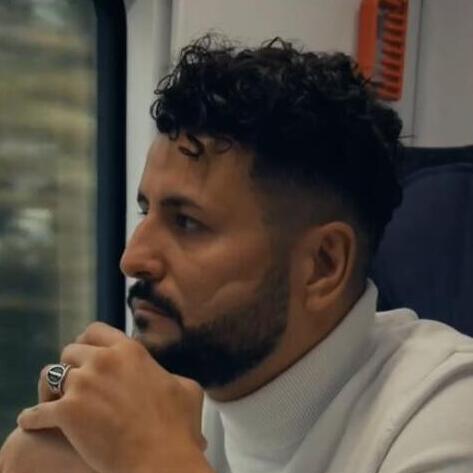 Ibrahim Arslan fährt Zug und schaut aus dem Fenster.