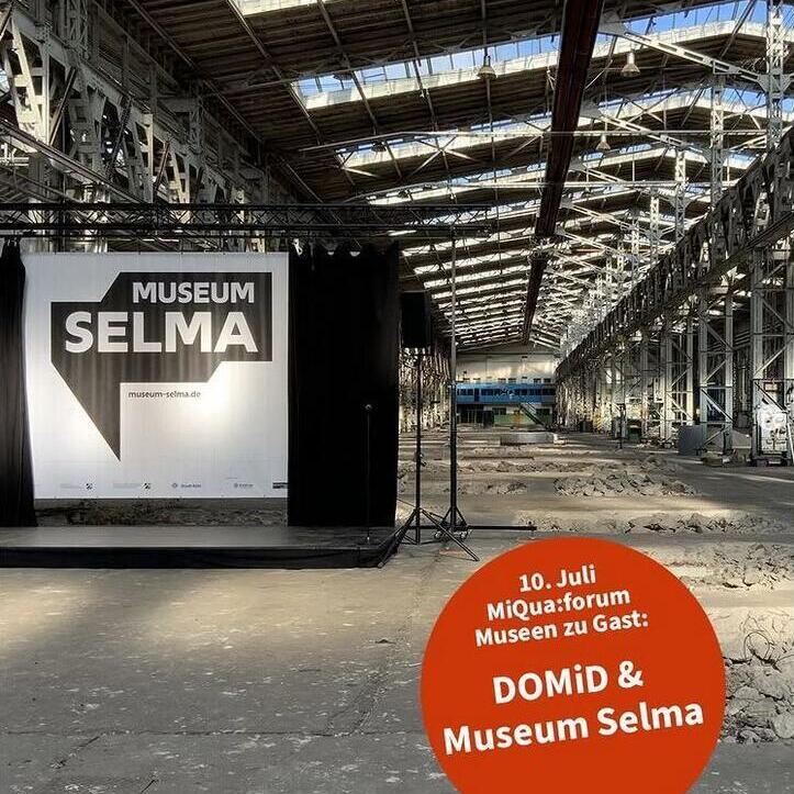 Auf dem Bild sieht man eine Fabrikhalle in der eine Leinwand mit dem Museum Selma Logo zu sehen ist. Im rechten Eck ist ein oranger Kreis eingefügt der den Text "10. Juli MiQua:forum Museen zu Gast DOMiD & Museum Selma" enthält.