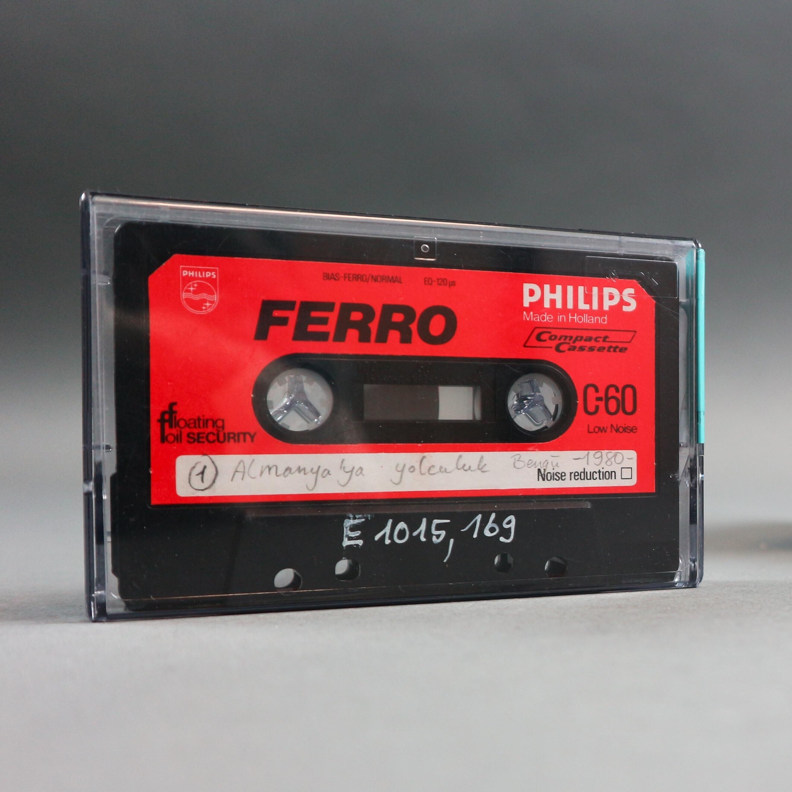 Schwarz-rote Kassette in Hülle mit handschriftlich beschriebenem Etikett.