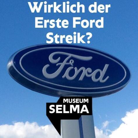 Man sieht ein großes Schild mit dem Ford-Logo. Im Hintergrund sieht man den blauen Himmel.