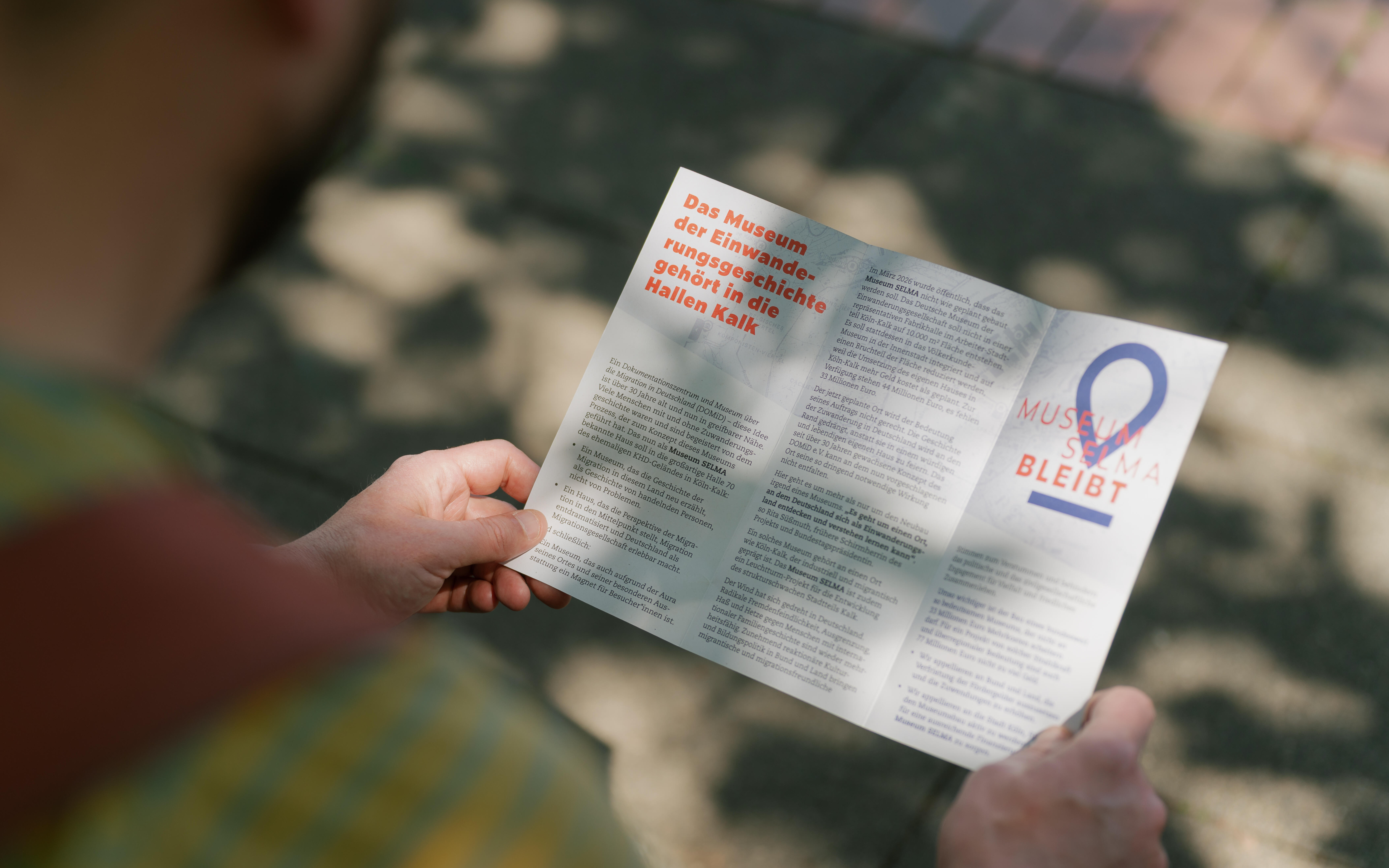 Eine Person betrachtet einen Info-Flyer der Initiative "Museum Selma bleibt".