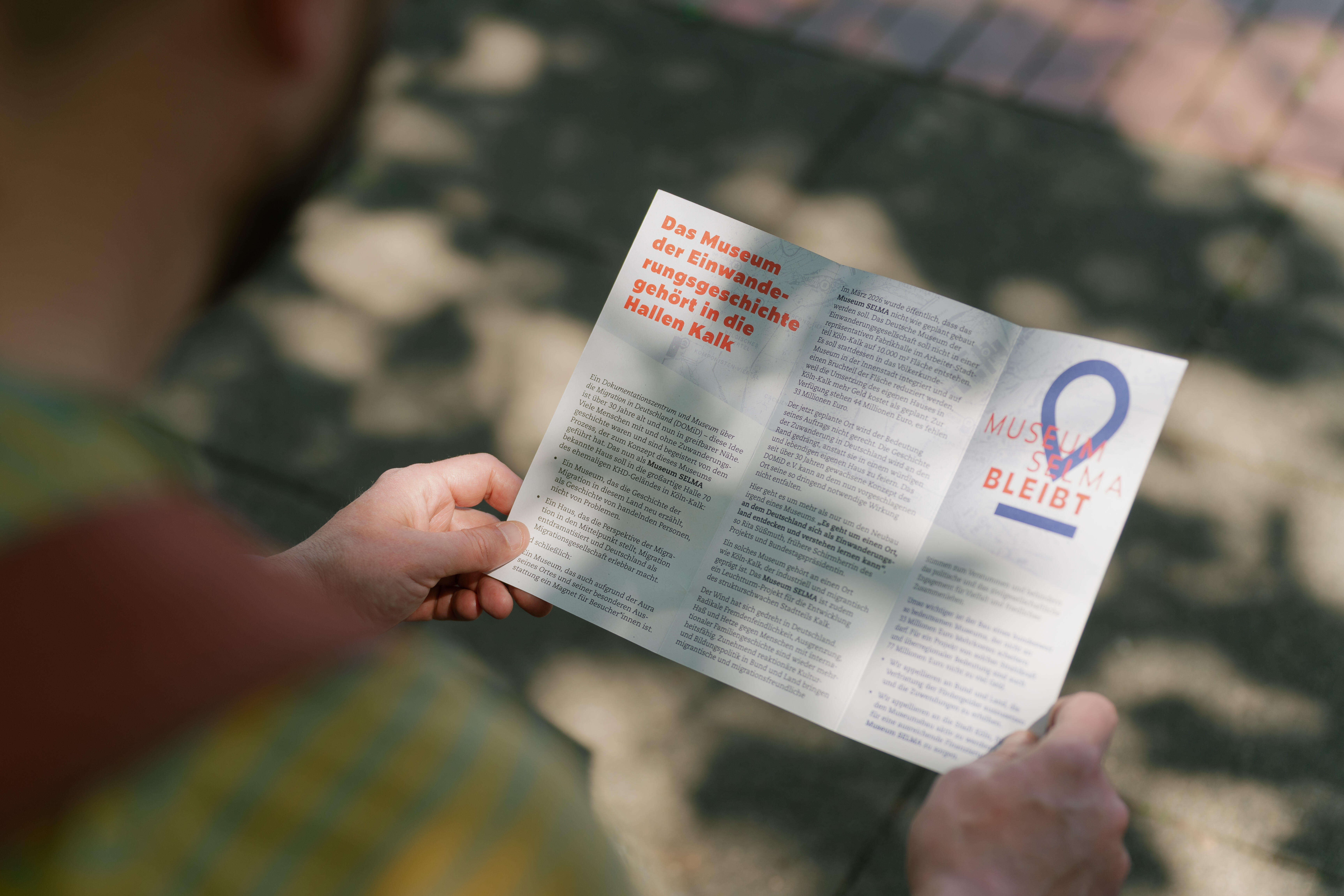 Eine Person betrachtet einen Info-Flyer der Initiative "Museum Selma bleibt".